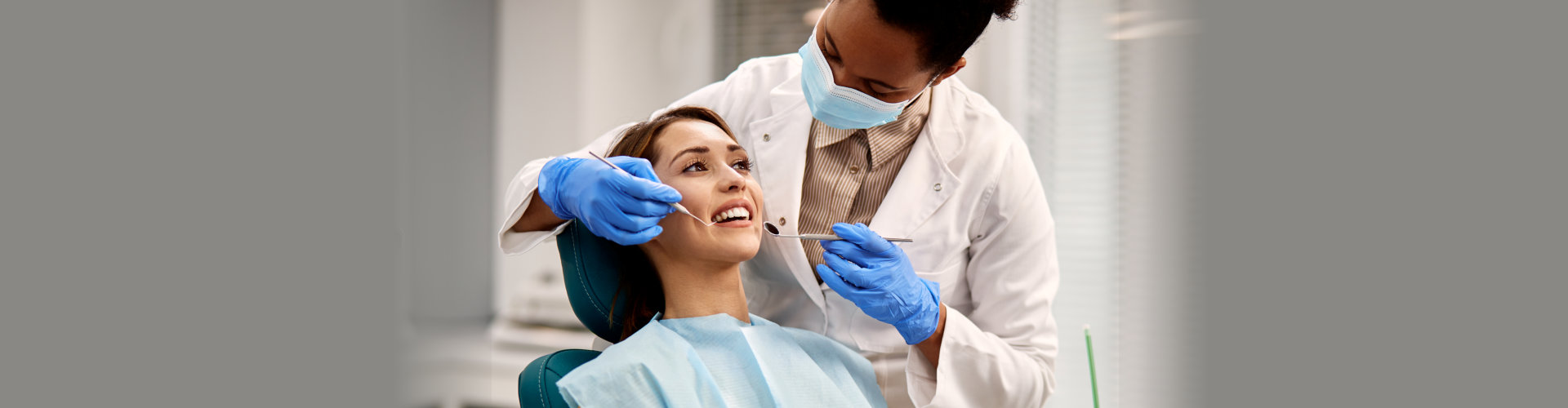 dentist examining teeth of her female patient during appointment at dental clinic. Focus is on young woman