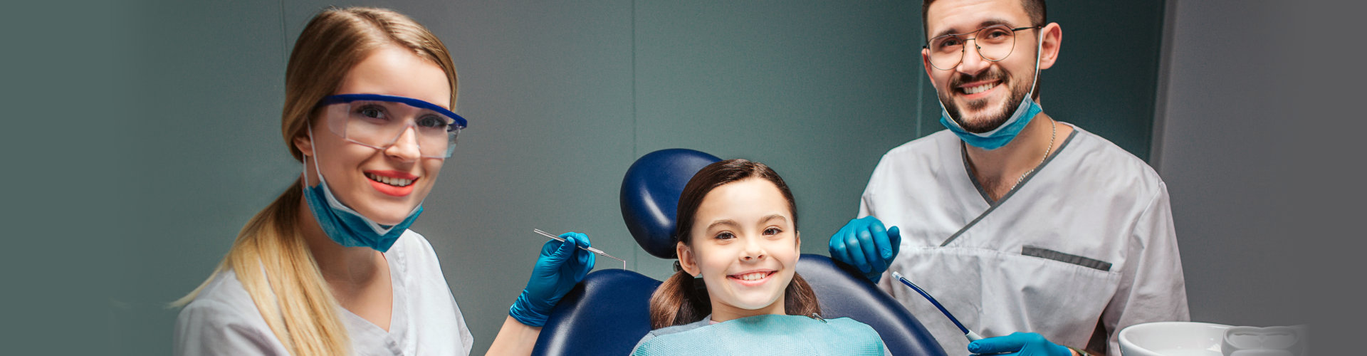 young girl smiling with two dentists beside her