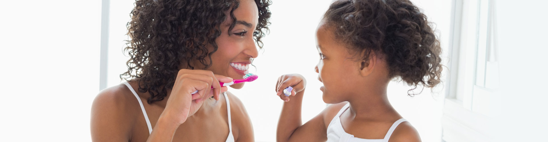 mother and daughter brushing their teeth